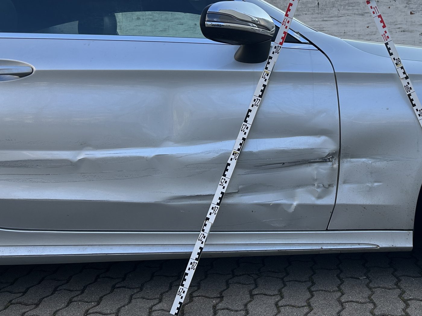 Schadenbild aus einer abgerechneten Akte: beschädigte Tür und vorderer Kotflügel, mit Messlatten dokumentiert