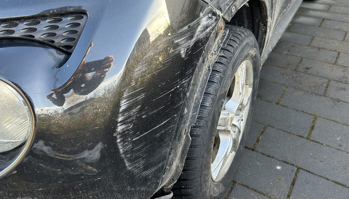 Beschädigte Fahrzeugfront mit aufgeschobenem Stoßfänger